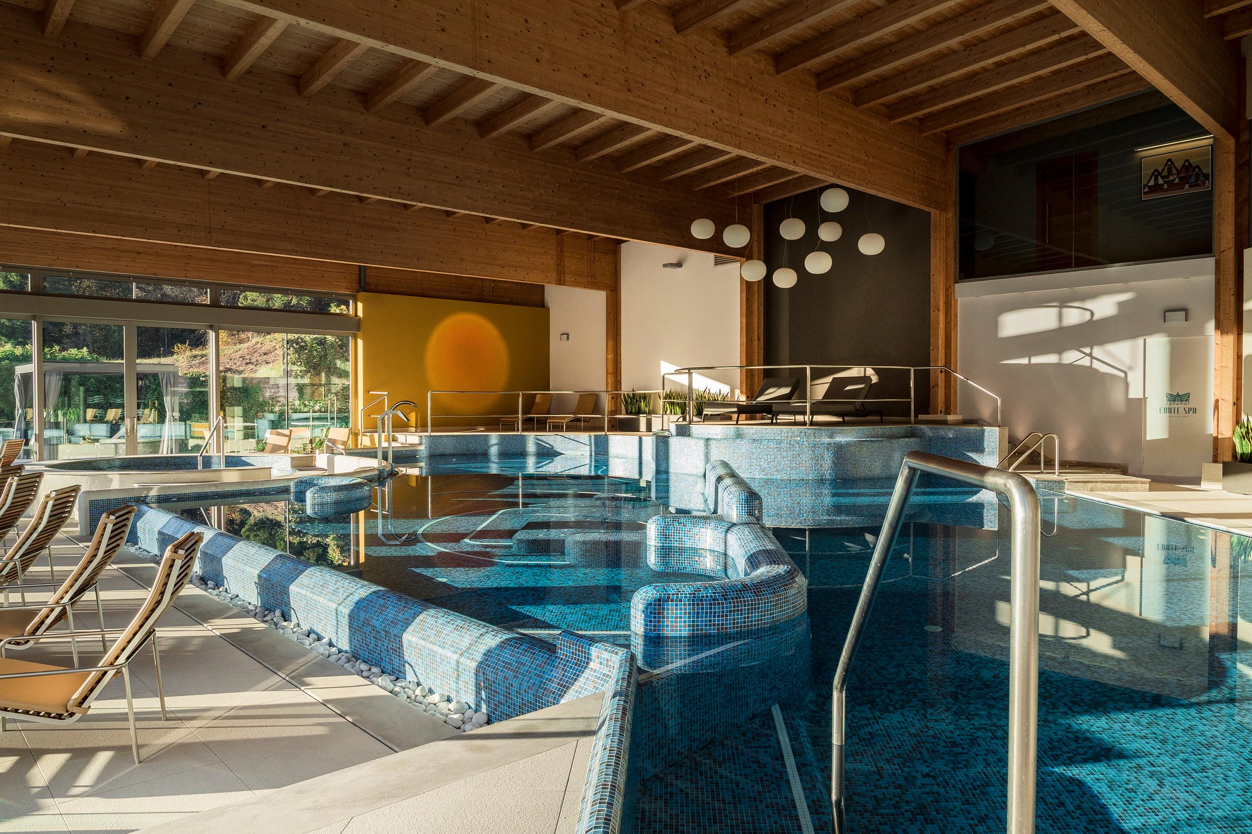 Piscina interna con elementi decorativi in legno e mosaico blu