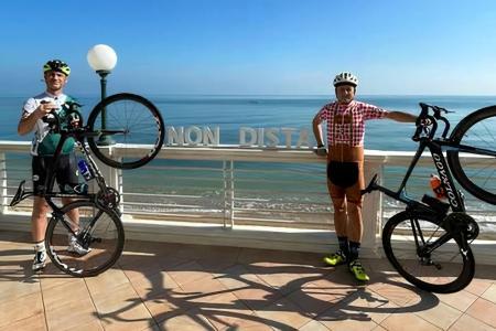 Due ciclisti posano con le loro bici davanti al mare