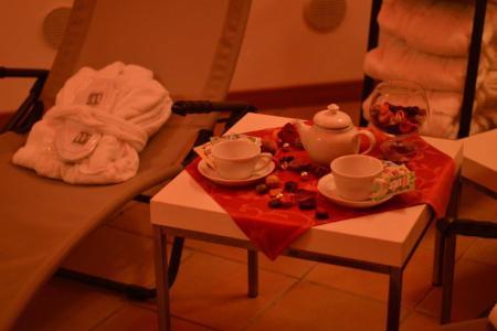 Un set per il tè accanto a una sedia con accappatoio e ciabatte