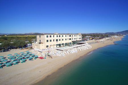 Spiaggia con ombrelloni verdi e edificio fronte mare, giornata limpida e soleggiata