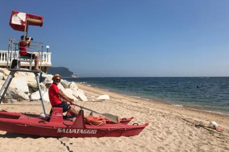 Bagnino in spiaggia con pattino di salvataggio e torretta di avvistamento