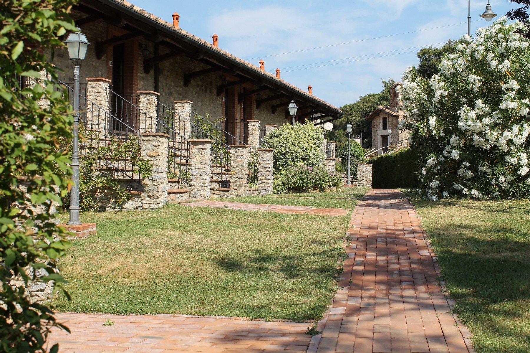 Camera boutique con travi in legno, arredi caldi e giardino privato