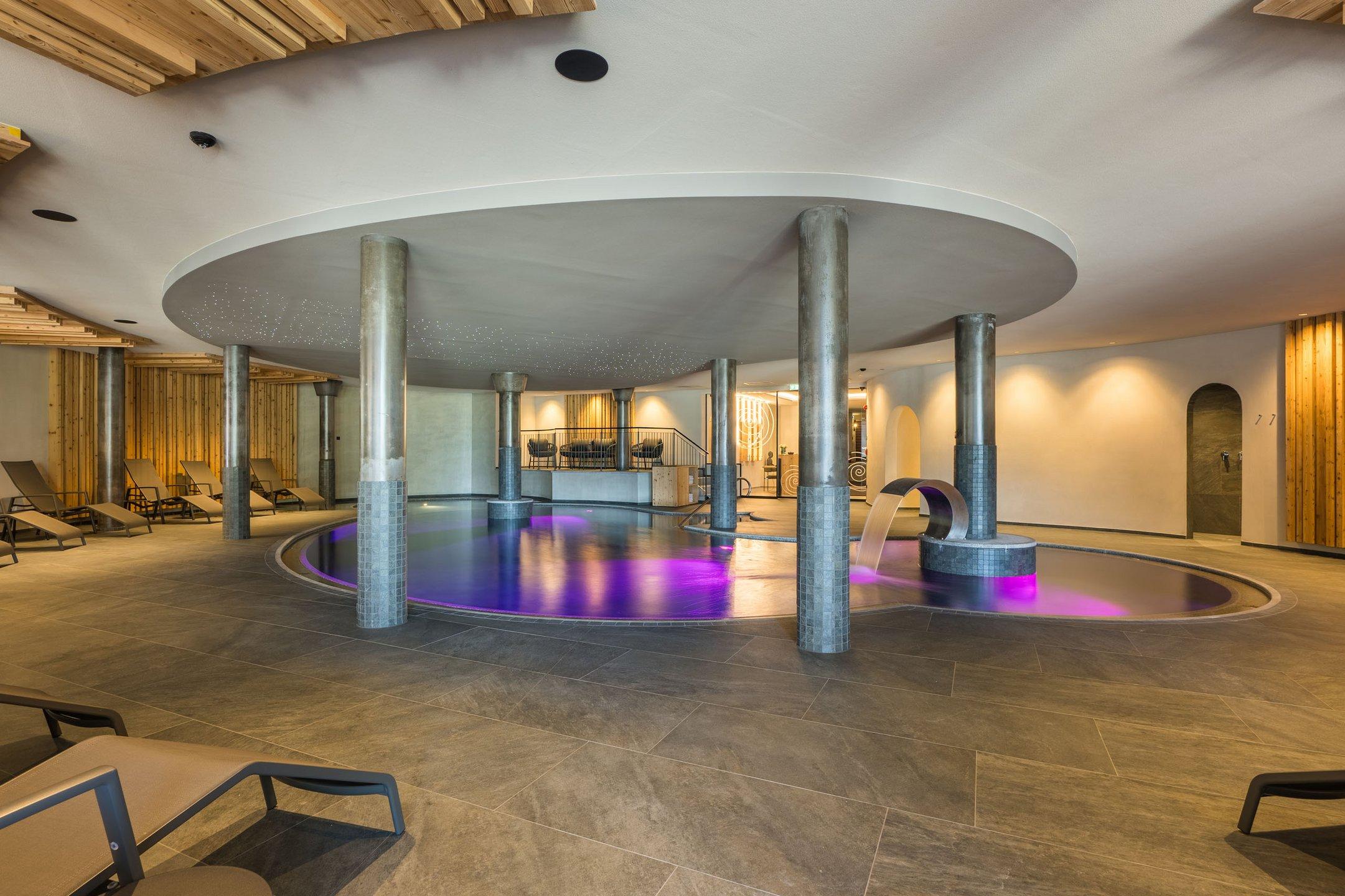 Centro benessere moderno con piscina, cascata e lettini
