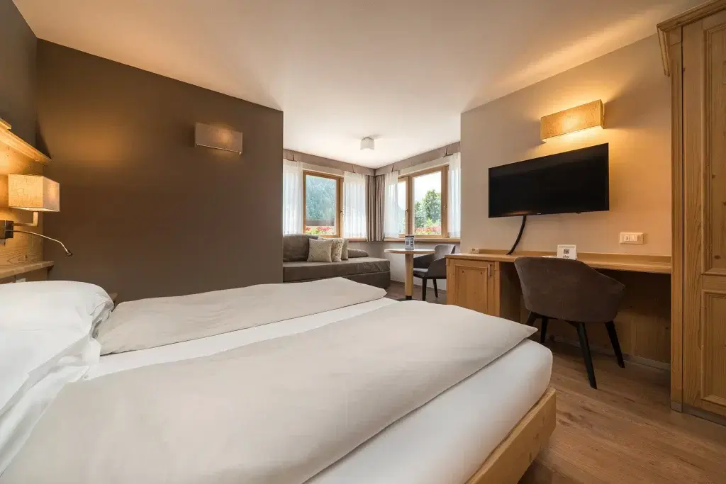 Camera d'albergo accogliente con letto matrimoniale, scrivania e vista panoramica dalle finestre