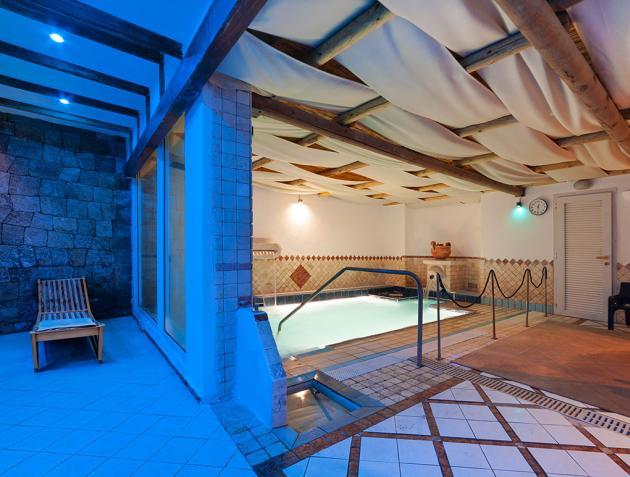 Piscina interna con arredi in legno e illuminazione soffusa