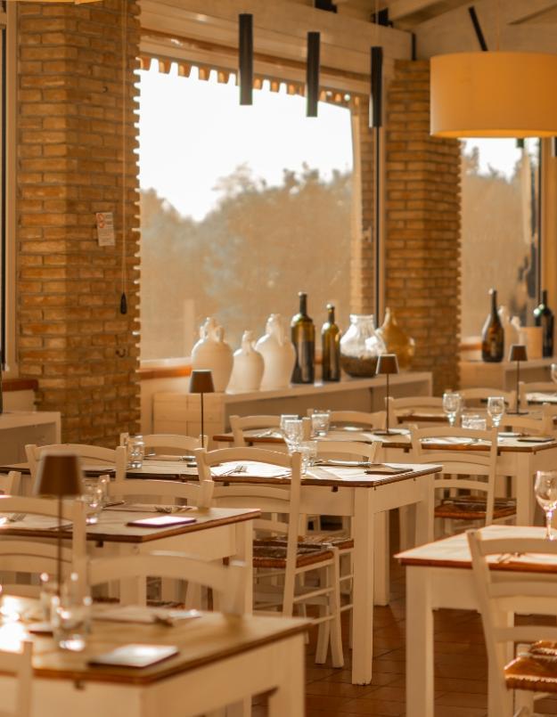 Ristorante accogliente con tavoli apparecchiati, luce calda e decorazioni in vetro