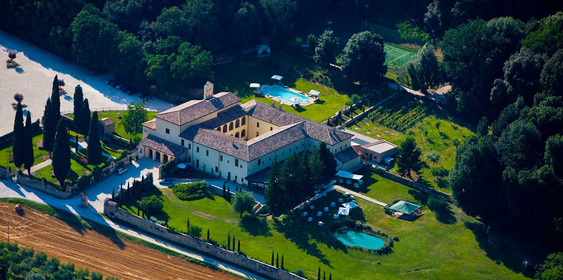 Vista aerea del resort San Pietro Sopra Le Acque circondata da boschi e campi umbri