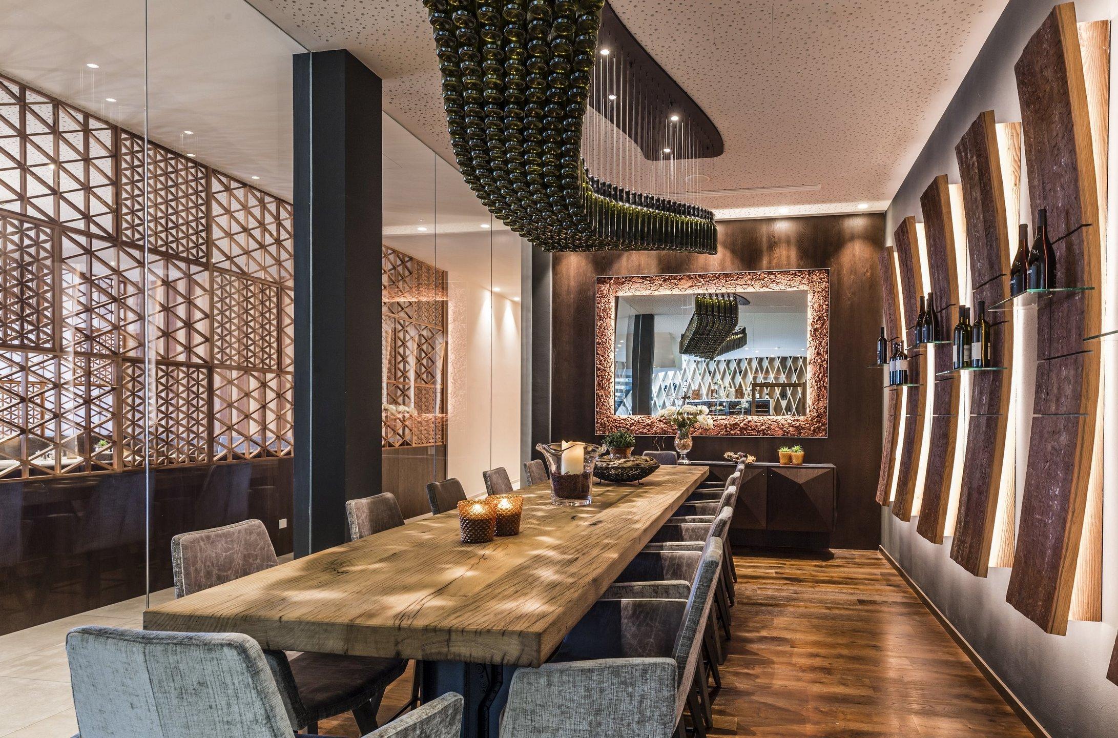 Sala degustazioni con tavolo lungo in legno e bottiglie di vino