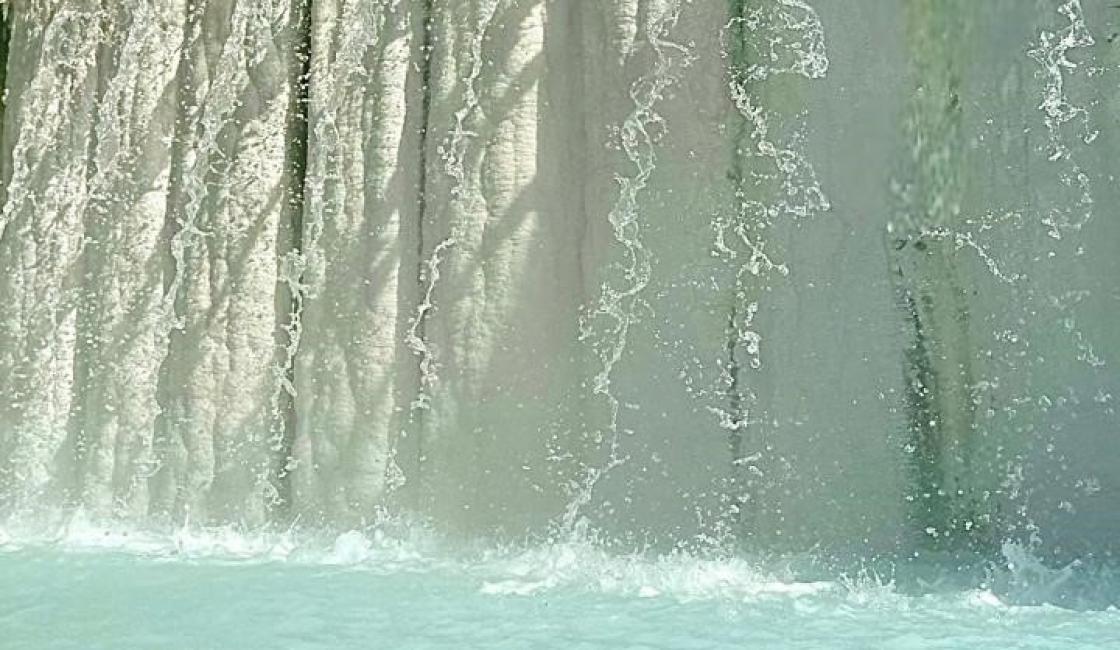 Cascata scintillante su marmo bianco sotto cielo azzurro intenso