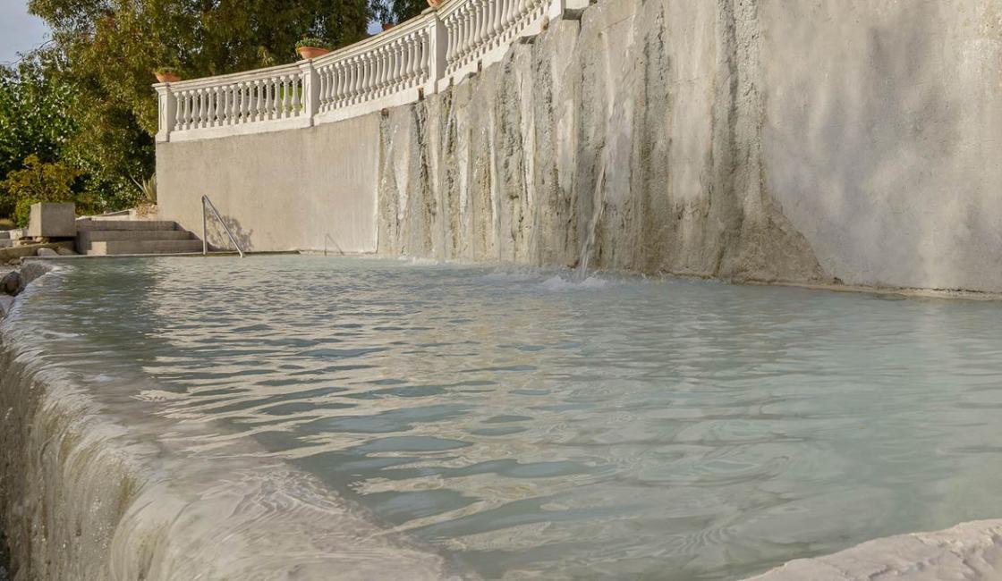 Piscina termale con cascata e vegetazione rigogliosa