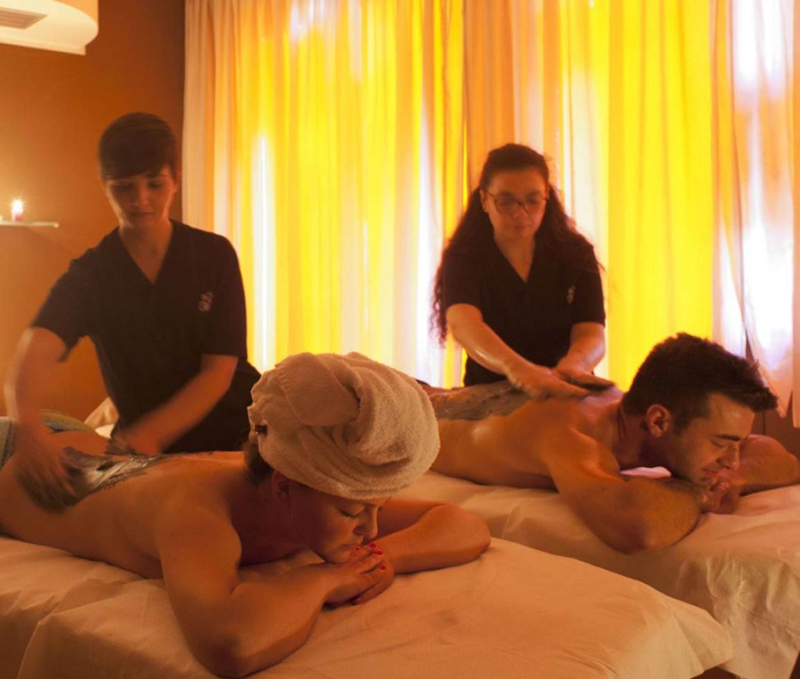 Due persone ricevono un massaggio rilassante in una stanza illuminata da candele