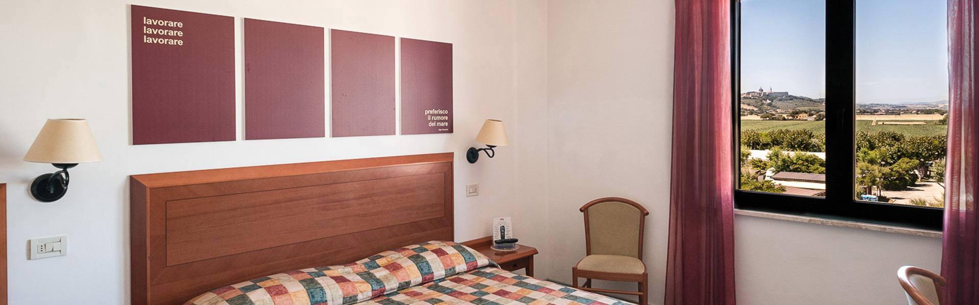Camera d'albergo con vista panoramica, letto matrimoniale e decorazioni minimaliste