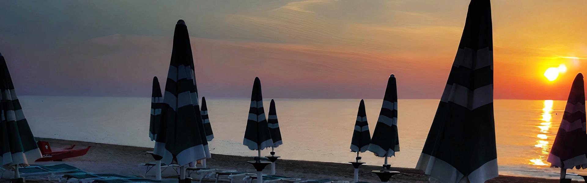 Spiaggia al tramonto con lettini e ombrelloni chiusi, atmosfera serena