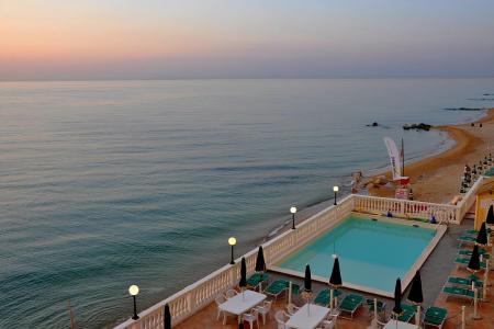 Piscina e spiaggia al tramonto, vista mare serena e rilassante