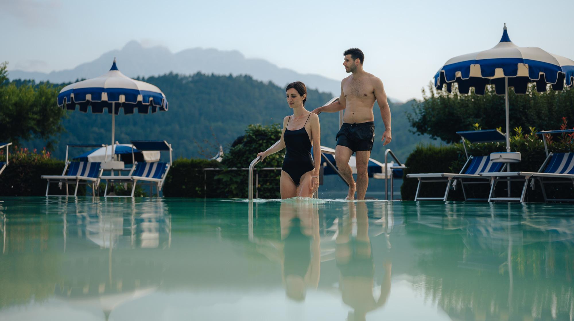 Coppia che entra nella piscina esterna del Parc Hotel Du Lac con vista sulle montagne