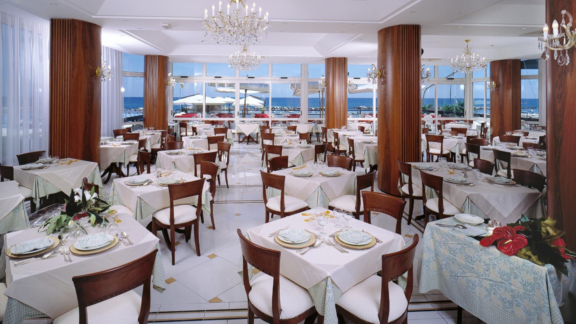 Ristorante elegante con vista mare, tavoli apparecchiati e lampadari scintillanti