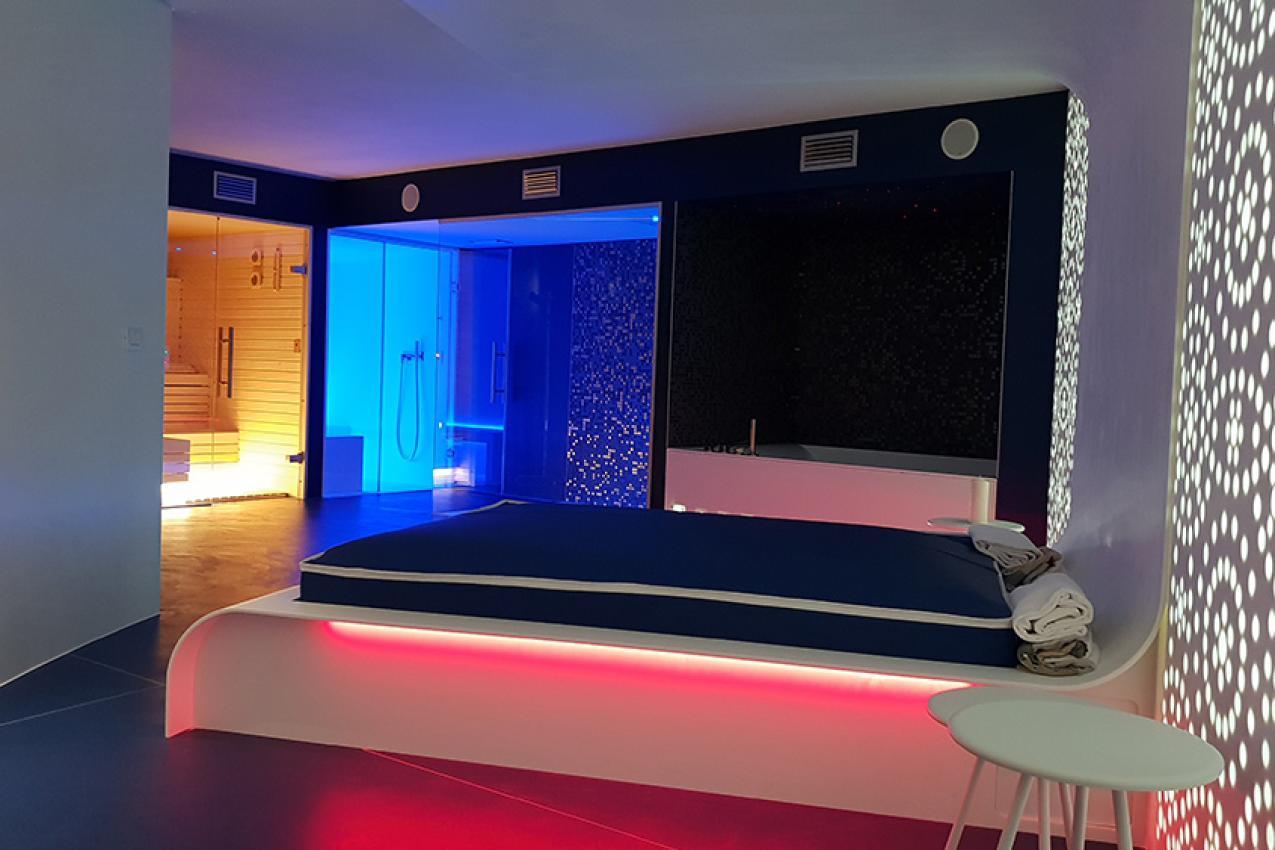 Sauna moderna con illuminazione colorata e porta in vetro
