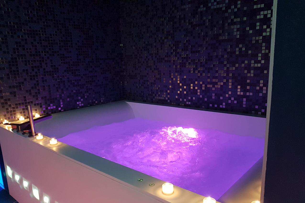 Vasca idromassaggio illuminata con luci viola e candele