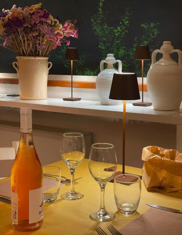 Tavola apparecchiata con bottiglia di vino, bicchieri e decorazioni floreali