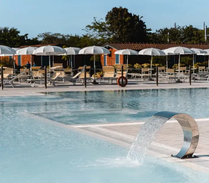 Piscina con ombrelloni bianchi e sedie a sdraio in un'area relax all'aperto