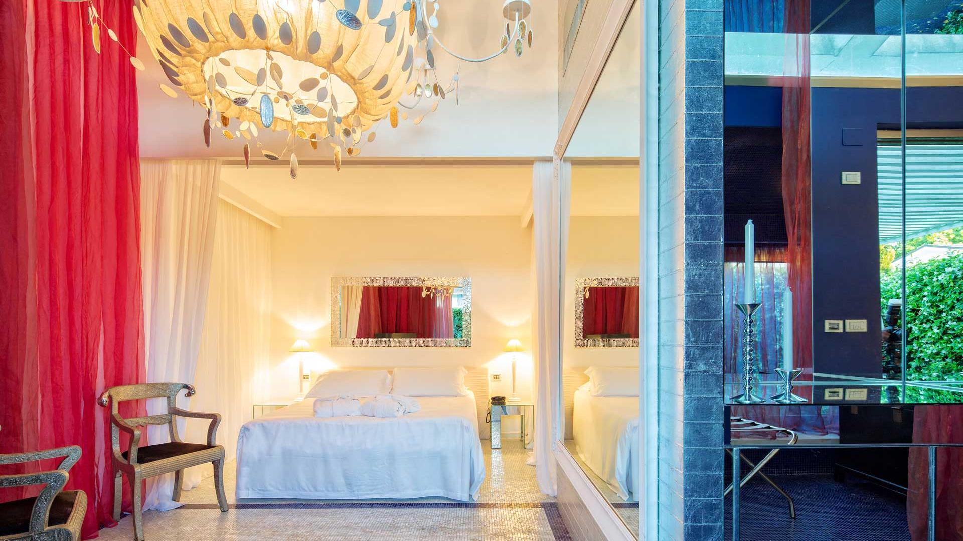 Camera elegante con lampadario artistico e tende rosse