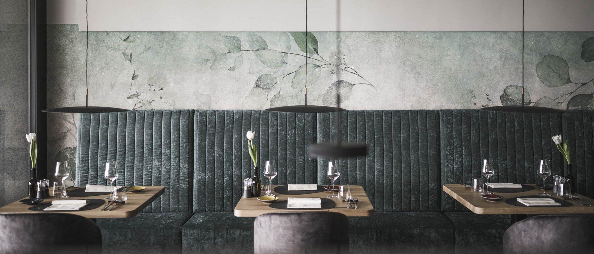 Moderno ristorante con sedute verdi e tavoli in legno